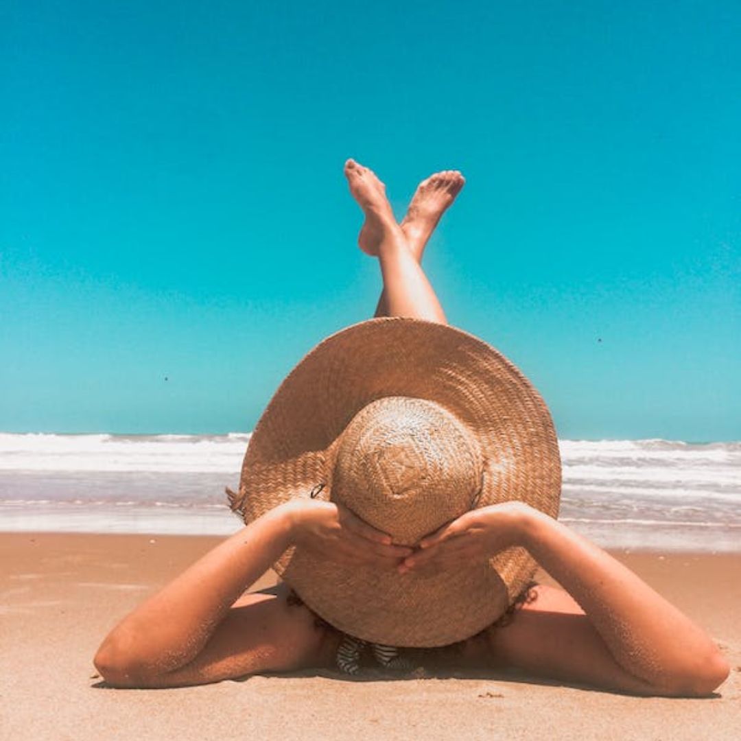 mujer con sombrero tumbada en la playa, vacaciones, primavera, embarazo, embarazada