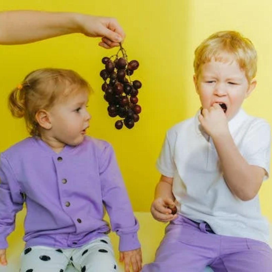 niño y niña con racimo de uvas, Cuentos para niños sobre los celos entre hermanos, envidia