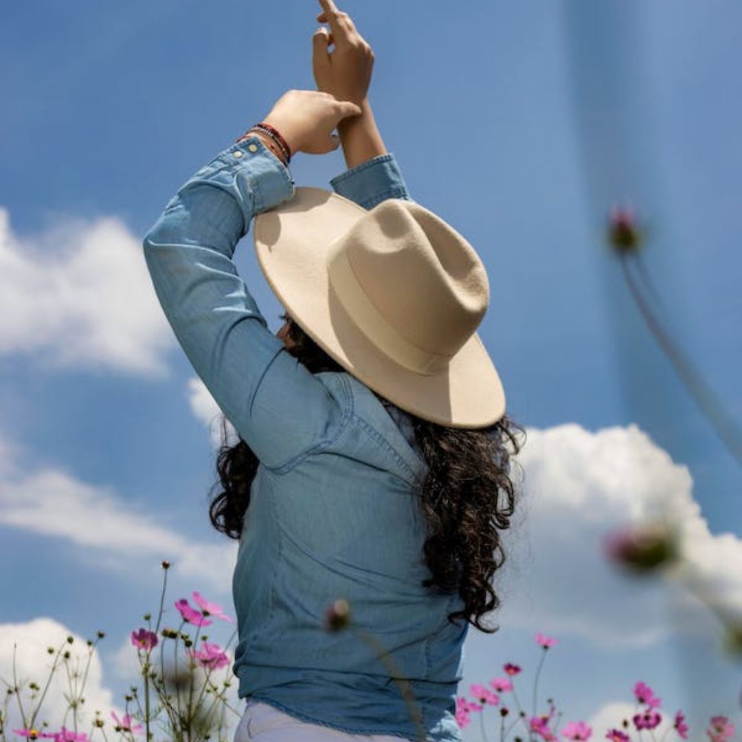 mujer de espaldas y con un sobrero entre flores, alergias, primavera